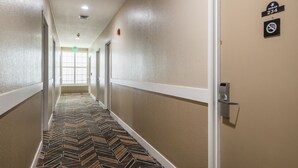 A hotel hallway with a patterned carpet, beige walls, and a door with a sign indicating room number 234. - Travel Inn (Sunnyvale)