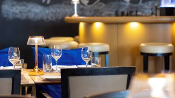 A restaurant interior with a blue tablecloth, wine glasses, and a chandelier.