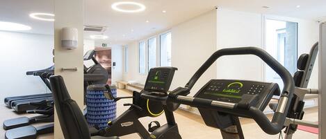 Un gimnasio con bicicletas estáticas, cintas de correr y máquinas de pesas.