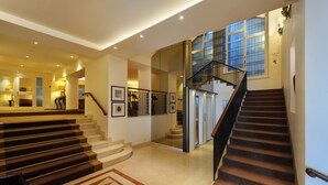 A spacious interior with a grand staircase, a well-lit hallway, and a view of the upper floor. - De la Paix (Lausanne)