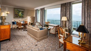 A hotel room with a dining area, a sofa, a desk, and a view of the sea. - De la Paix (Lausanne)