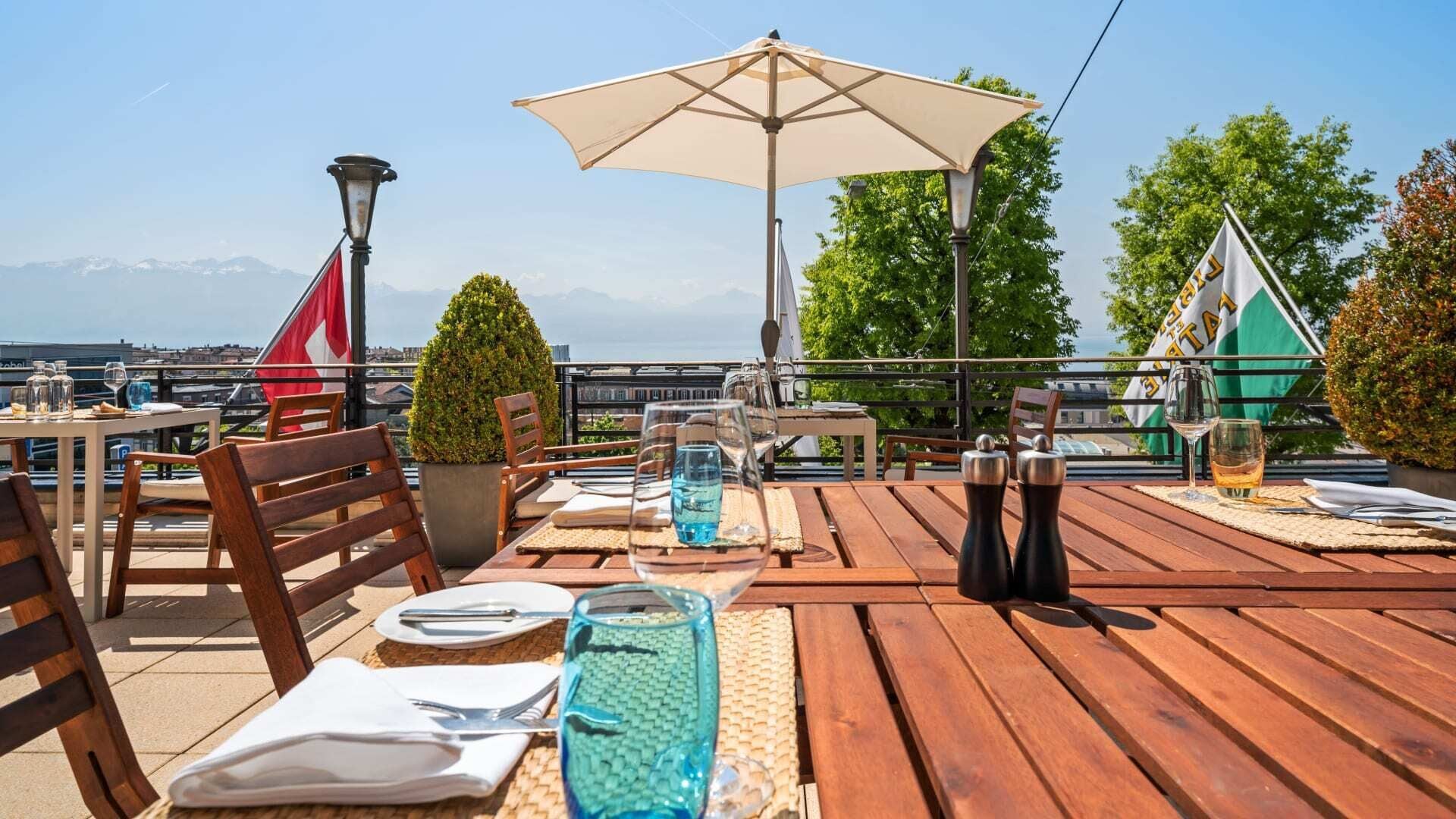 An outdoor dining area with wooden tables, chairs, and a large umbrella.