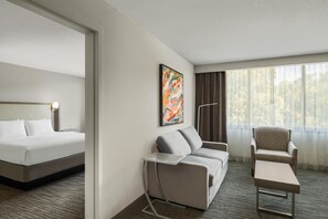 A hotel room with a bed, a sofa, a chair, a small table, and a window with curtains. - Best Western Premier Rockville Hotel & Suites (Rockville)