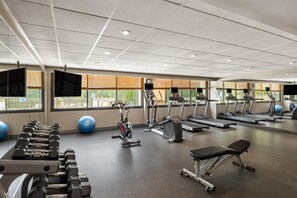 Une salle de sport équipée de tapis de course, de vélos d’exercice et de poids libres.