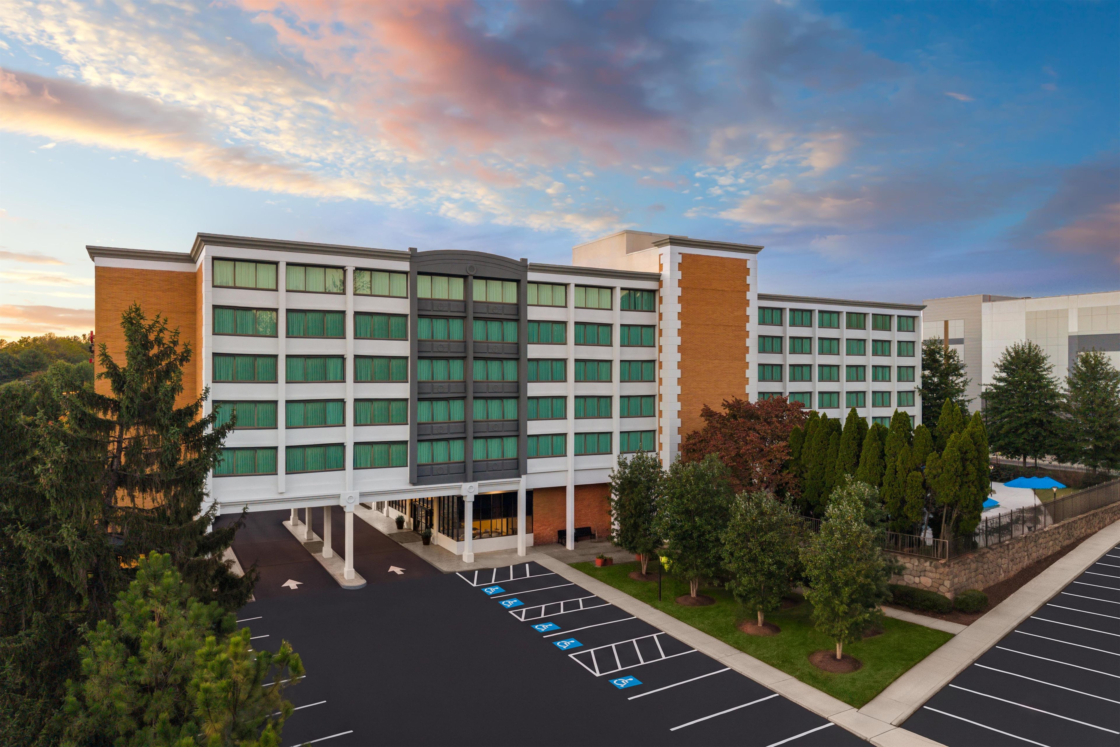 A multi-story hotel with a parking lot and landscaped areas.