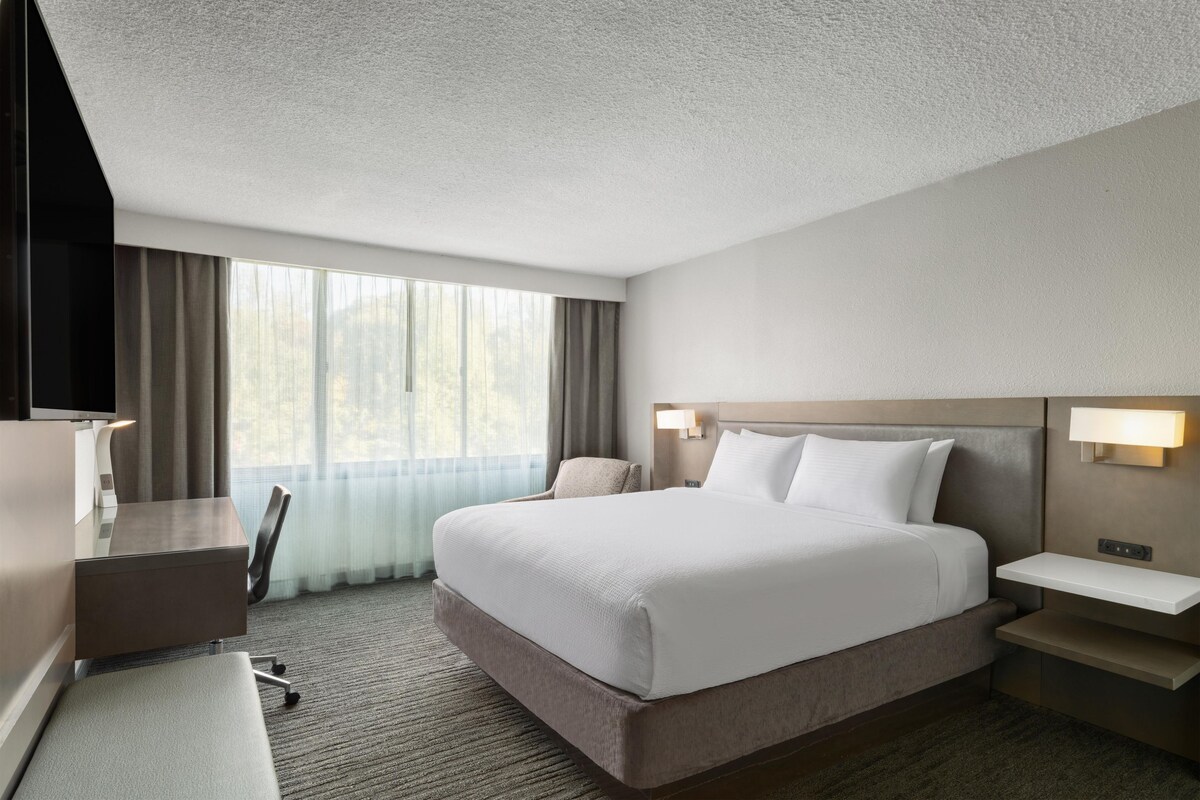 Une chambre d’hôtel avec un grand lit, des tables de chevet, un bureau et une chaise.