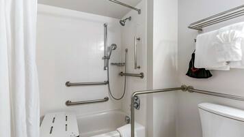 Une salle de bain équipée d’une douche, de toilettes et de barres d’appui.