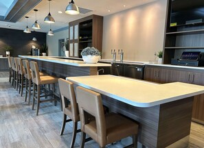 Una cocina moderna con una isla central, taburetes de bar, iluminación colgante y electrodomésticos integrados.