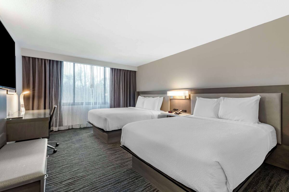 Une chambre d’hôtel avec deux lits, un bureau et une chaise.