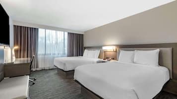 Een hotelkamer met twee bedden, een bureau en een stoel.