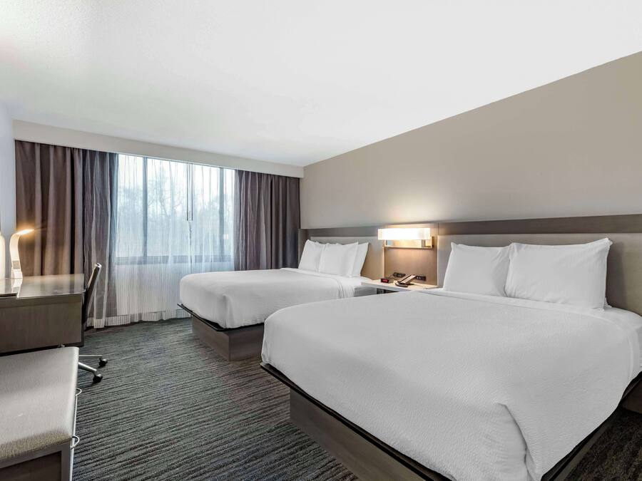 Een hotelkamer met twee bedden, een bureau en een stoel.