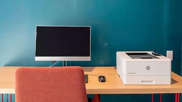 A workspace with a computer monitor, HP LaserJet printer, and a red chair.