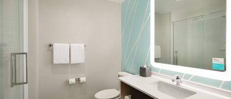A modern bathroom with a glass shower enclosure, a white toilet, a sink with a mirror, and a towel rack.