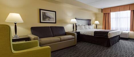 A hotel room with a sofa, a bed, two bedside tables, and a window with curtains.