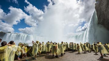 Un grupo de personas con abrigos impermeables amarillos de pie frente a una cascada.
