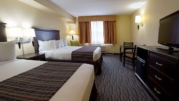 Ein Hotelzimmer mit zwei Betten, einem Schreibtisch, einem Fernseher und einem Schminktisch.