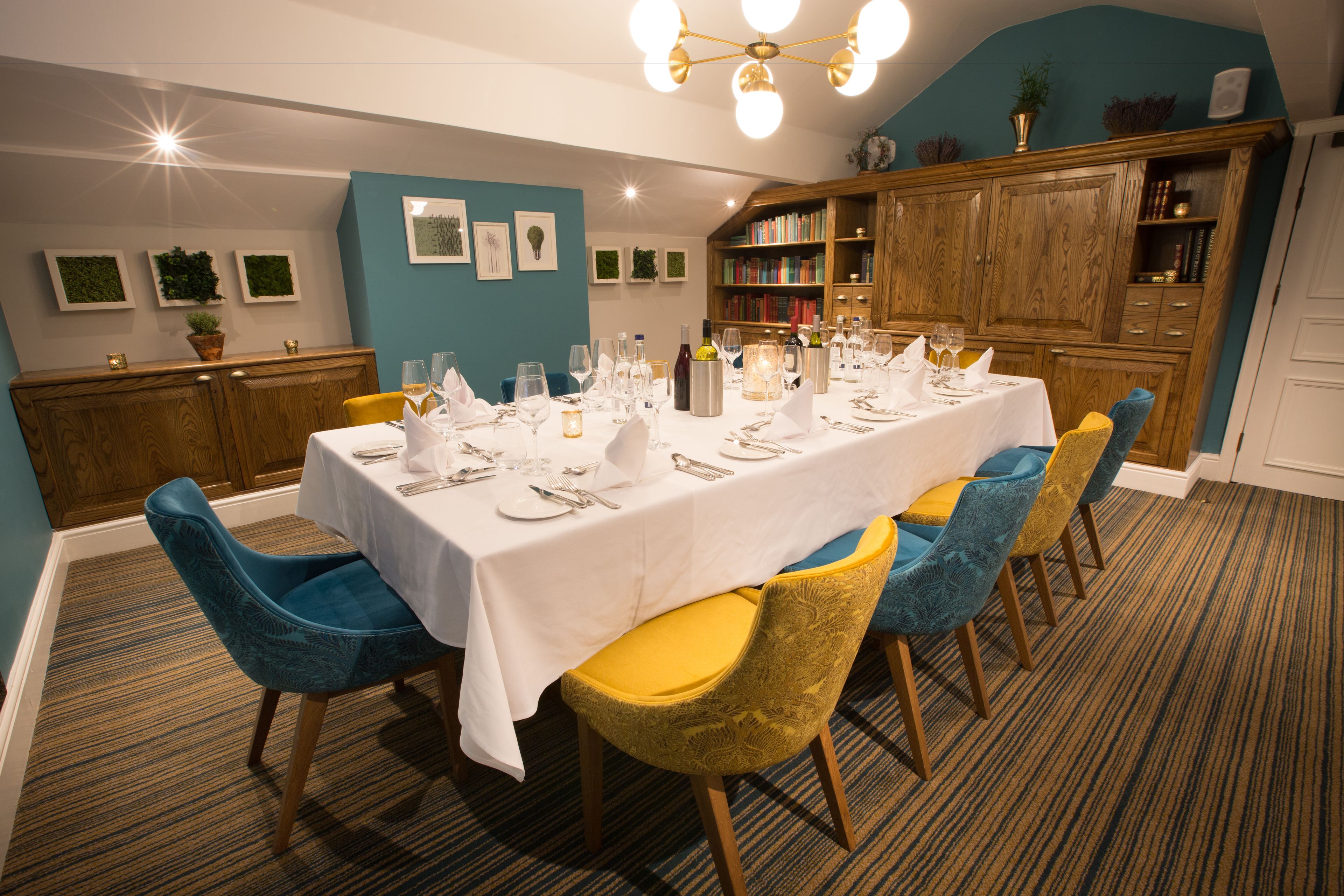 A dining area with a long table set for six, surrounded by blue and yellow chairs.
