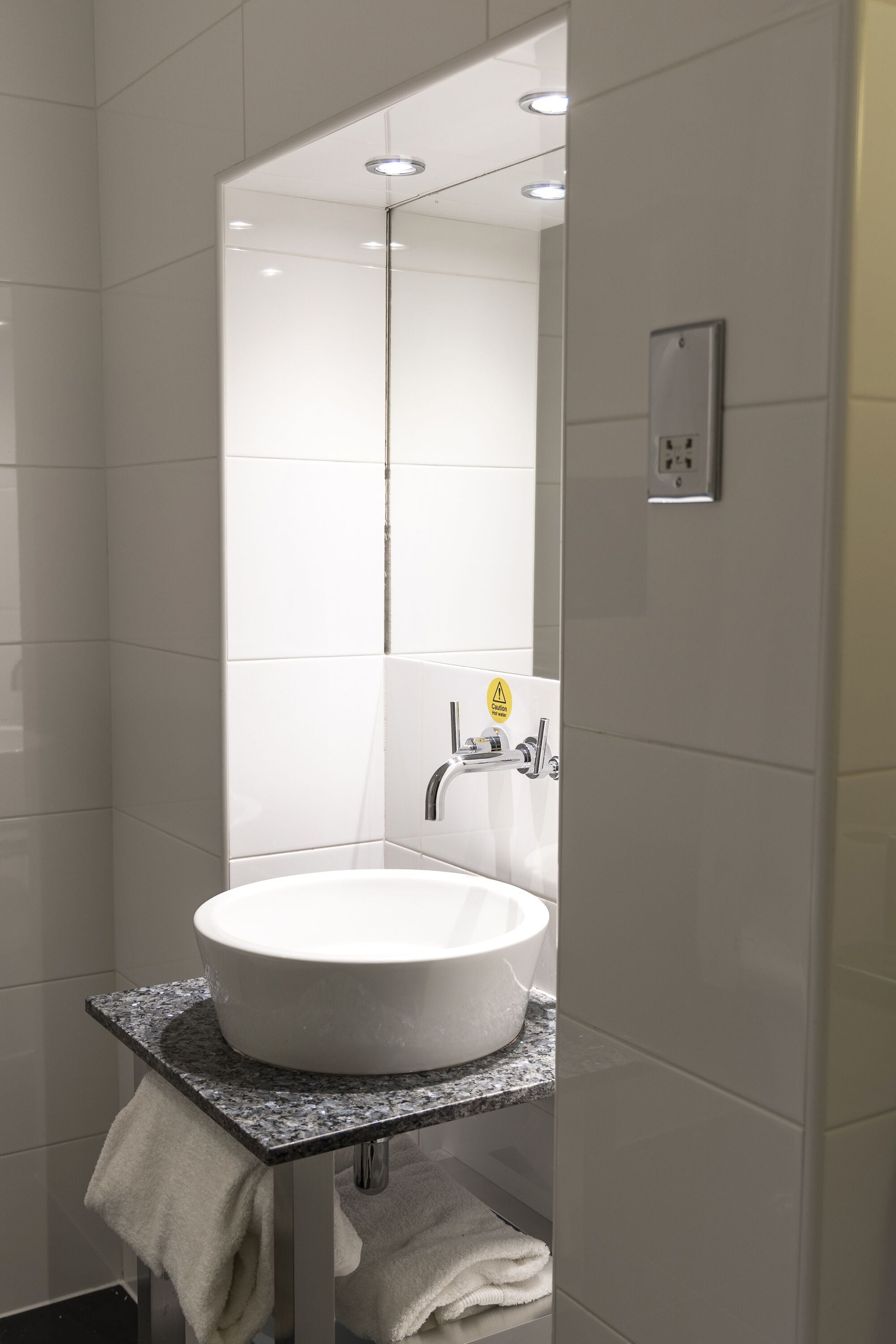 A modern bathroom with a white sink, a mirror, and a towel rack.