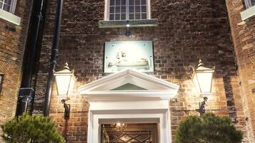A brick building with a white entrance and two potted plants.