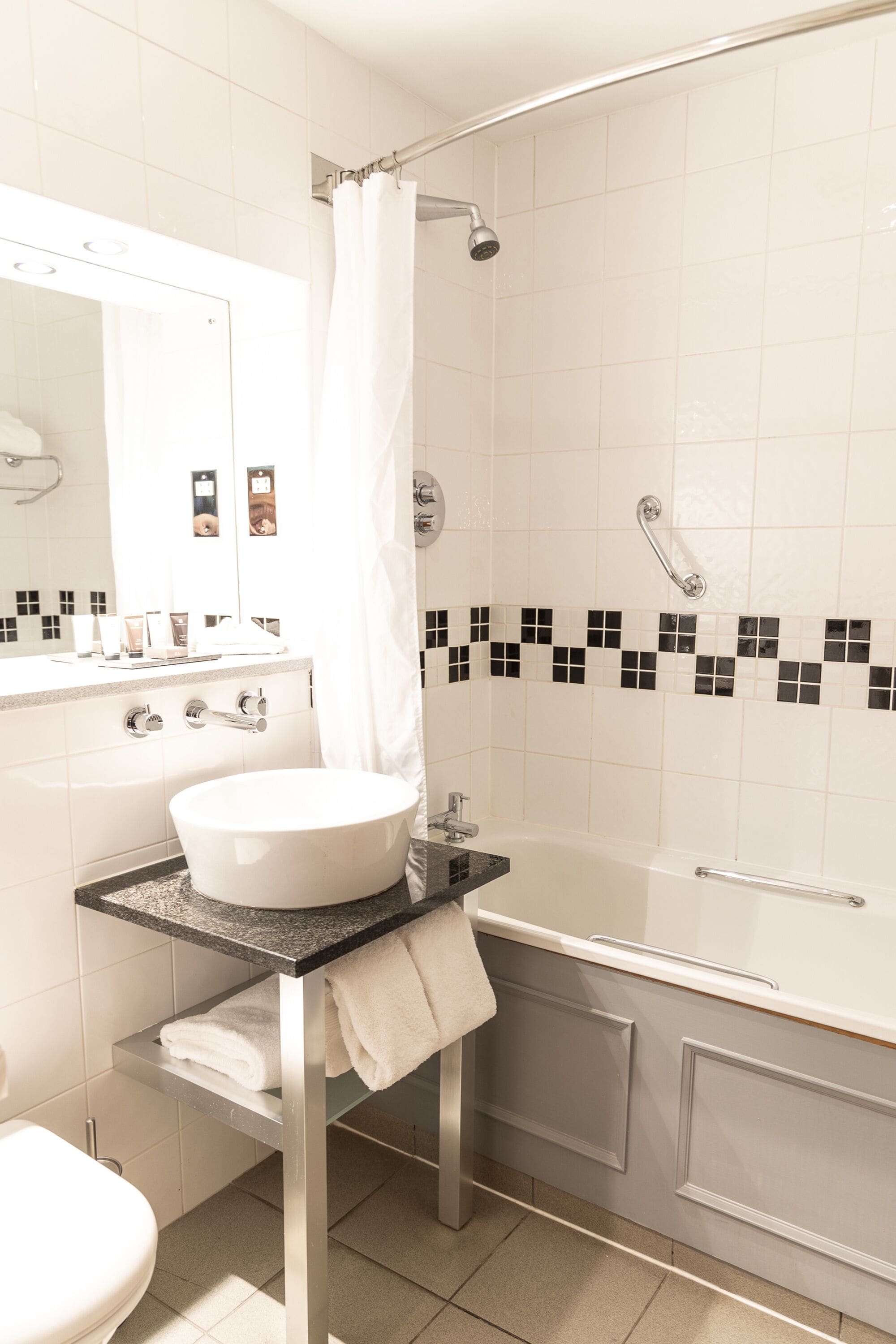 Un baño moderno con lavamanos, tocador y bañera blancos.