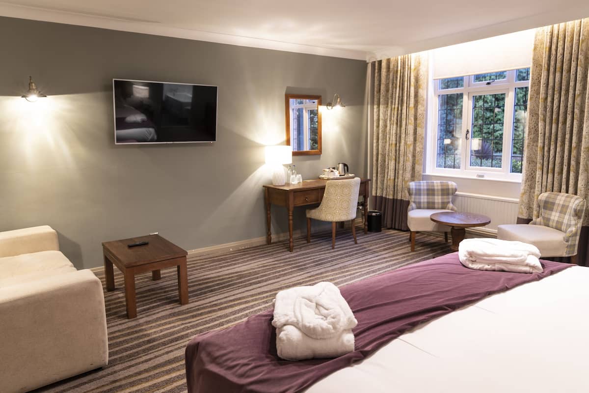 A hotel room with a bed, a desk, a chair, a TV, and a window with curtains.