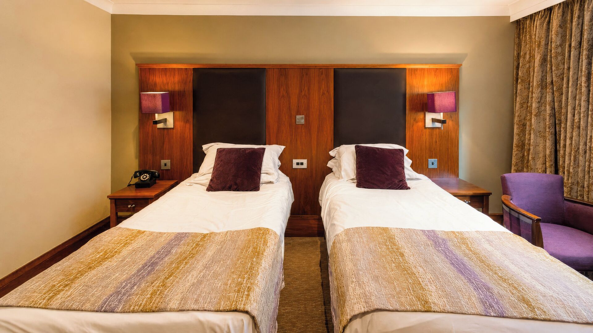 A hotel room with two beds, a chair, and a telephone.