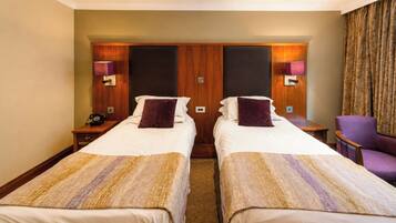 A hotel room with two beds, a chair, and a telephone.