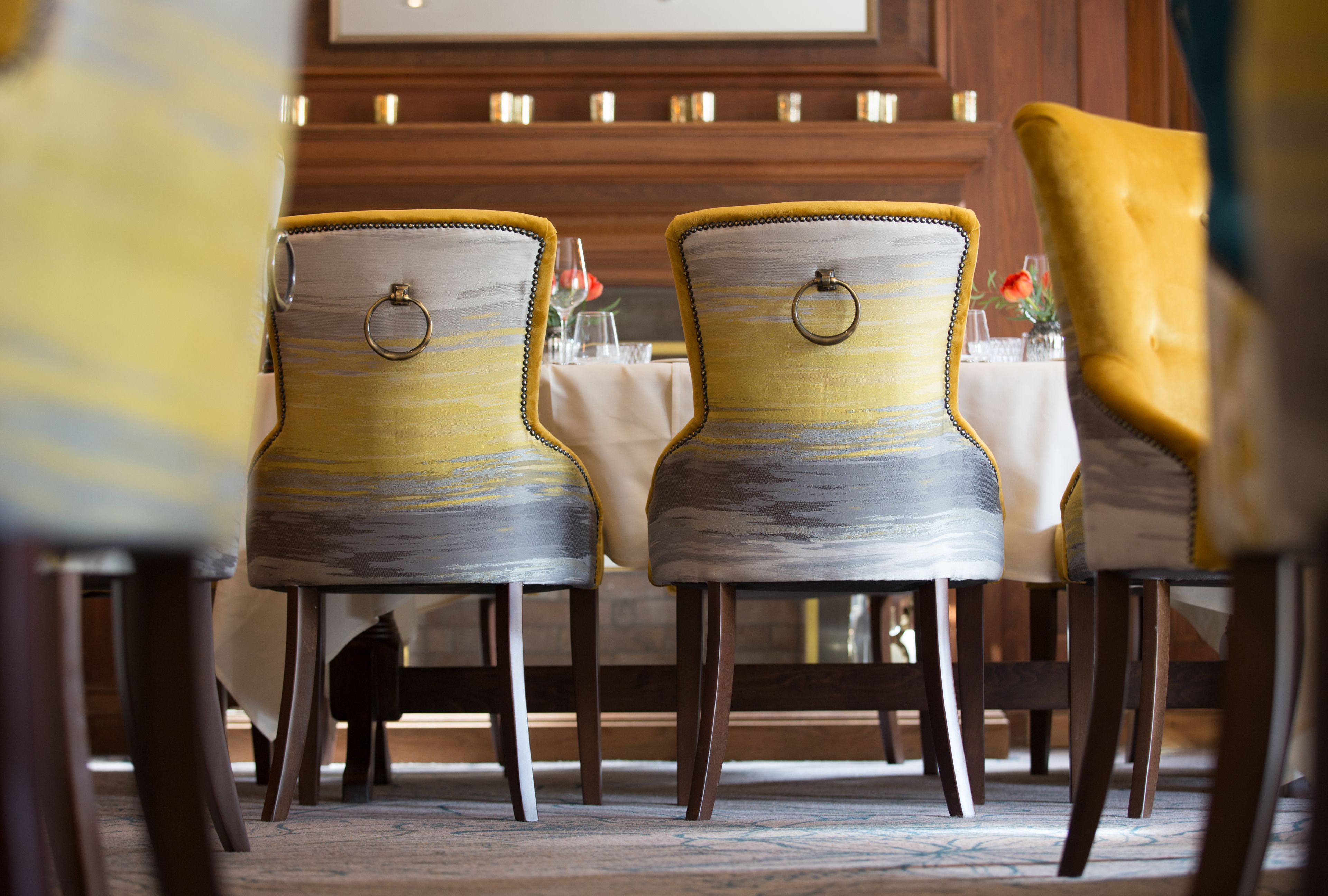 A dining area with wooden chairs and a yellow upholstered chair.