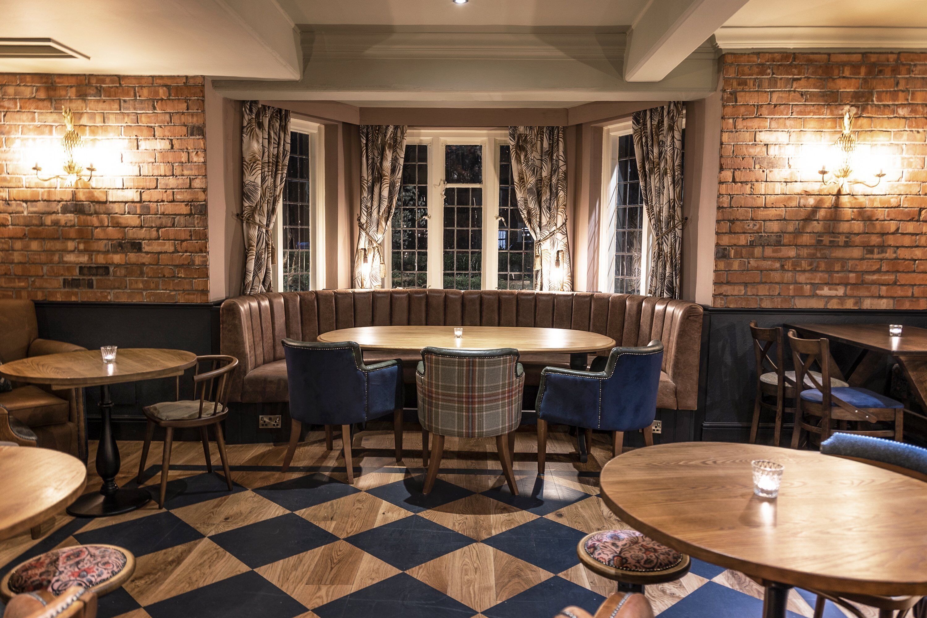 Un restaurante acogedor con pared de ladrillo, mesas de madera y sillas tapizadas en azul.
