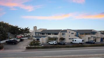 A multi-story motel with a parking lot, a signboard, and a clear sky.