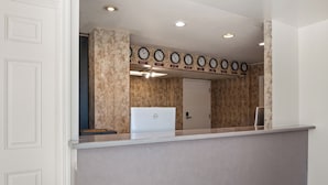 A reception area with a desk, a computer, and a wall with clocks.