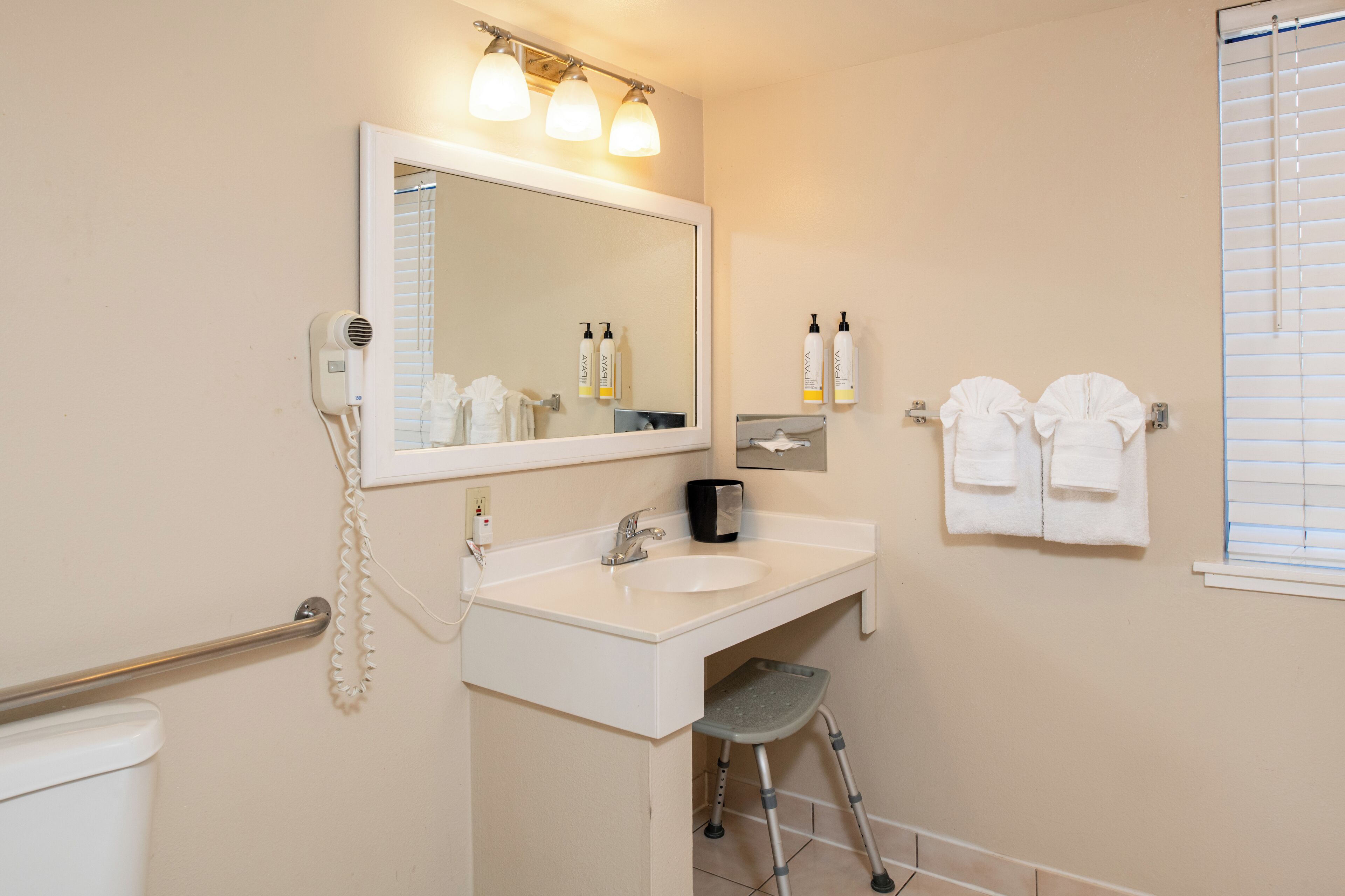 A bathroom with a sink, mirror, towel rack, and a step stool.