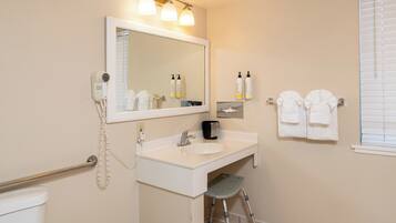 A bathroom with a sink, mirror, towel rack, and a step stool.