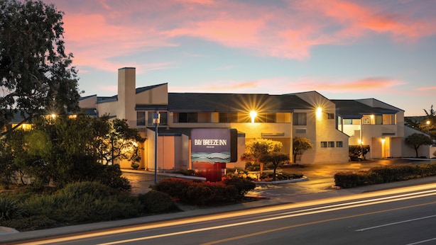 A hotel with a prominent sign, a parking lot, and a road with light trails.