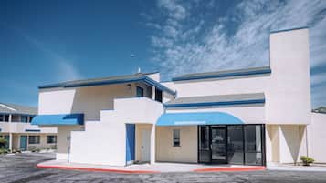 Un hotel moderno con tetto piatto, tenda parasole blu e cielo sereno.