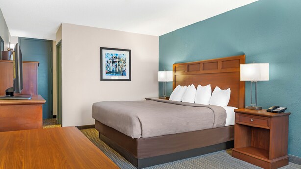 A hotel room with a bed, bedside tables, a desk, and a framed picture on the wall. - Red Lion Inn & Suites Bucyrus North (Bucyrus)