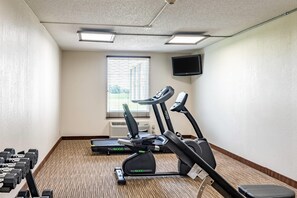 A gym with treadmills, a stationary bike, and dumbbells.
