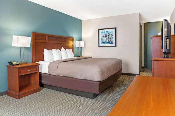 A hotel room with a bed, bedside tables, a TV, and a framed picture on the wall. - Red Lion Inn & Suites Bucyrus North (Bucyrus)