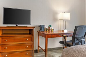 A hotel room with a TV, wooden dresser, desk with a lamp, and a chair. - Red Lion Inn & Suites Bucyrus North (Bucyrus)