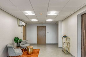 A hallway with a seating area, a plant, a small table, and a decorative stand.
