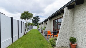 Un sendero estrecho que conduce a un edificio con fachada blanca y una fila de equipos de aire acondicionado.