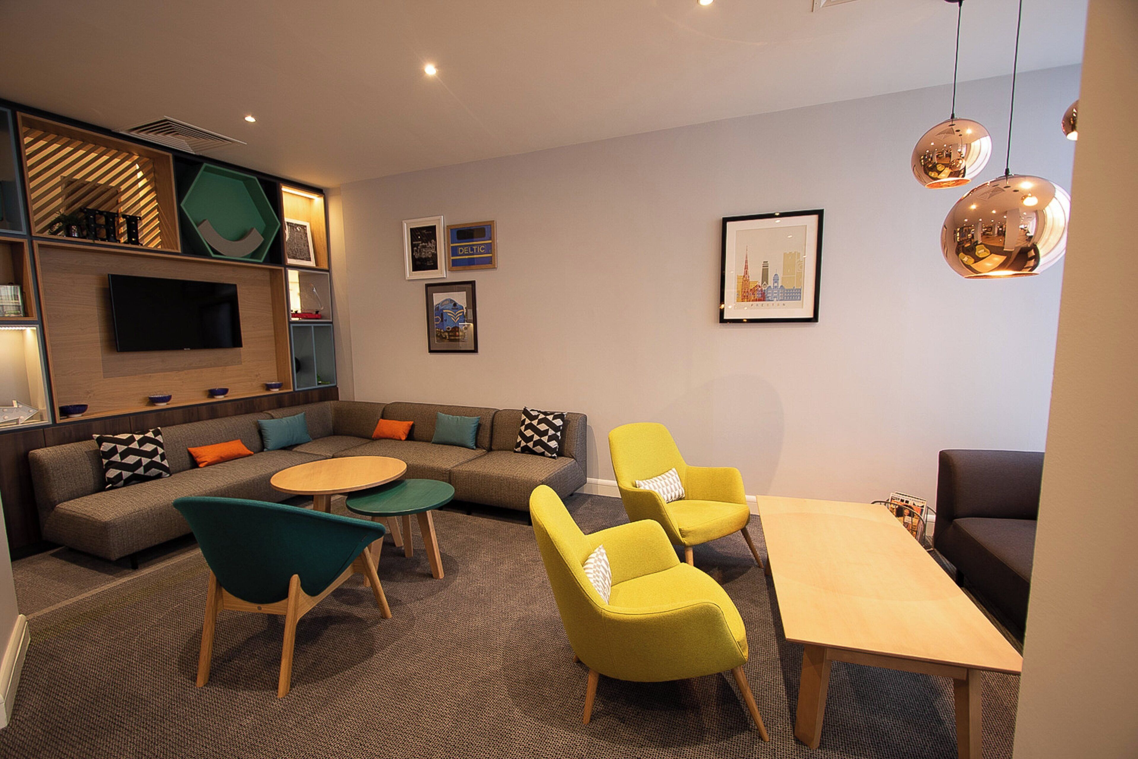 Una sala moderna con un sofá, dos sillones, una mesa de centro y un televisor montado en la pared.