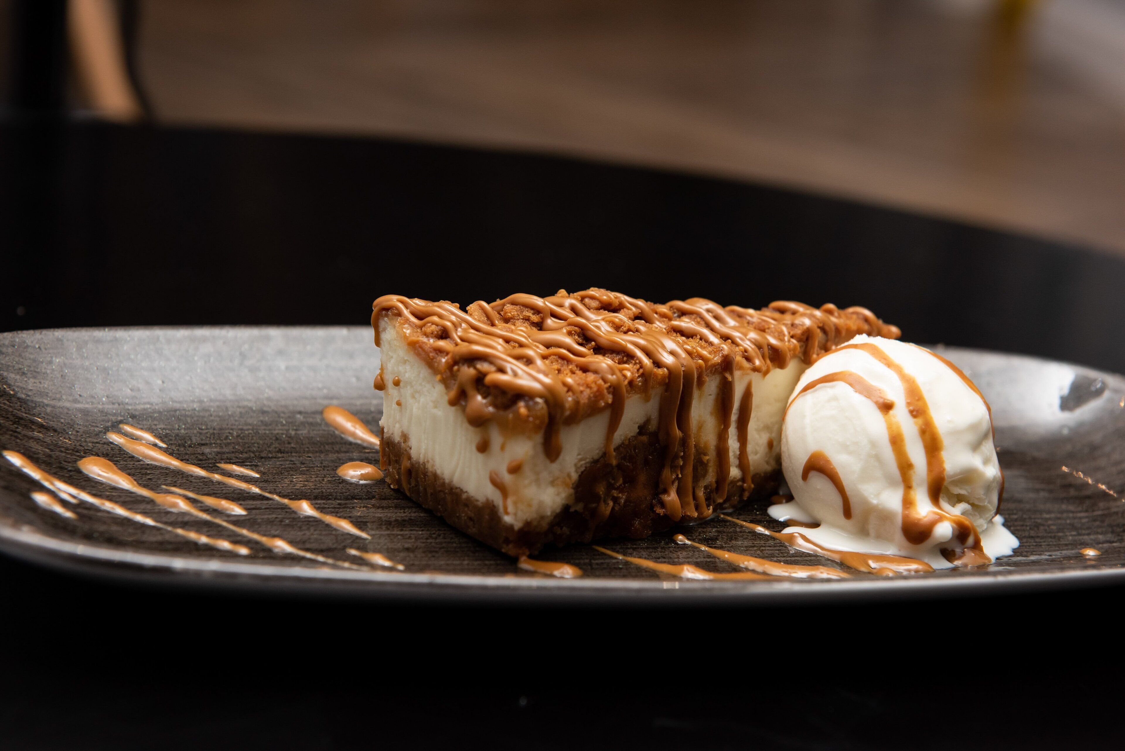 A dessert with caramel drizzle on a dark plate.
