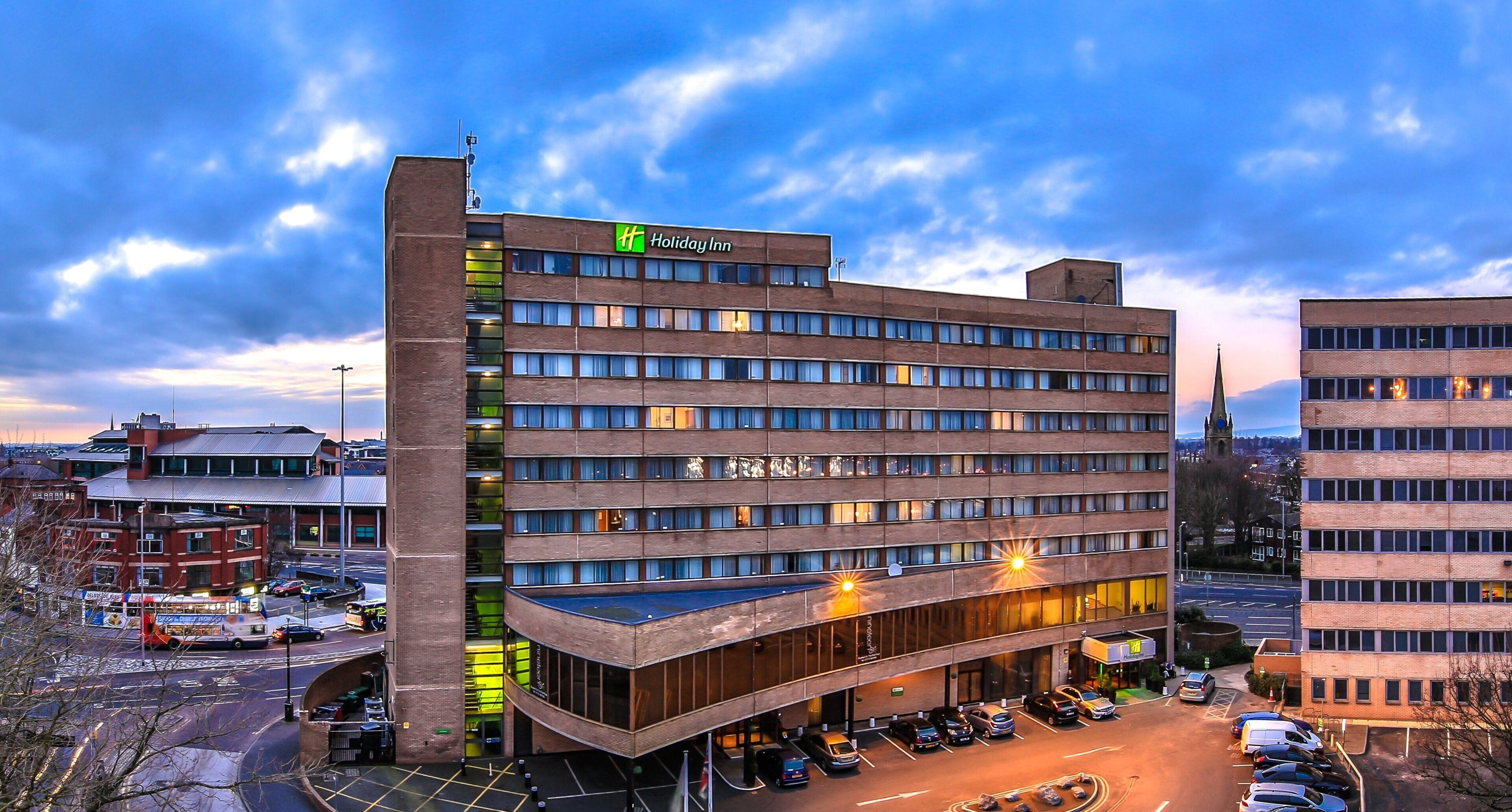 Un hotel Holiday Inn de varios pisos con estacionamiento y vista a la calle.