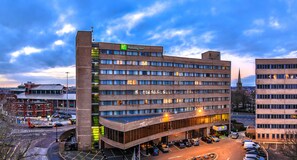 A multi-story Holiday Inn hotel with a parking lot and a street view.