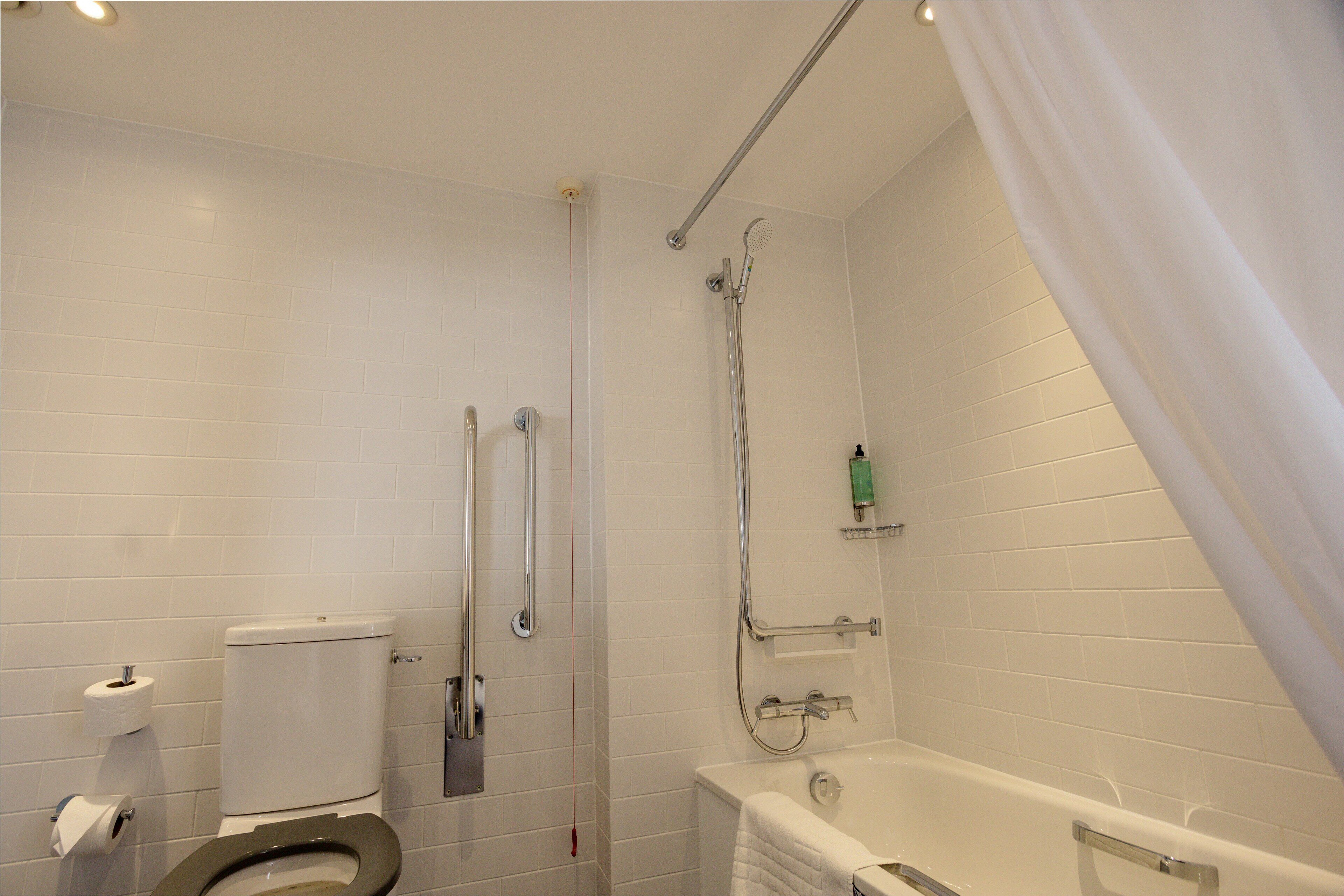 Een badkamer met toilet, douche en bad.