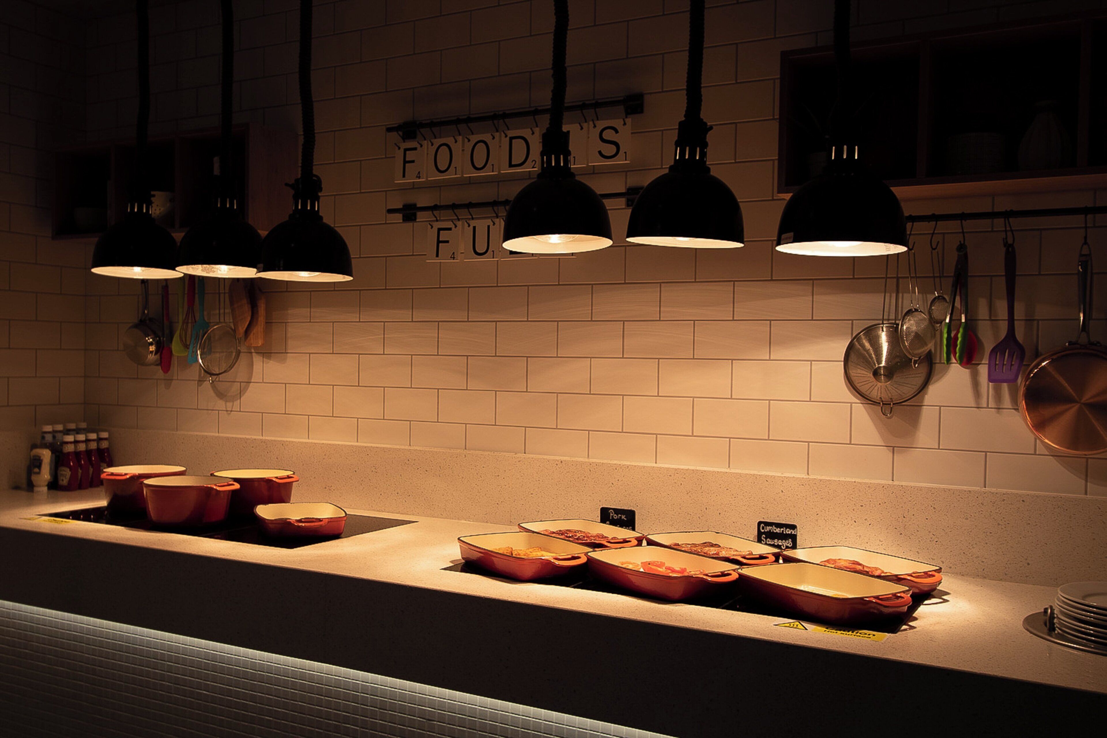 A kitchen with a long countertop, hanging pots, and a sign above indicating food storage areas.