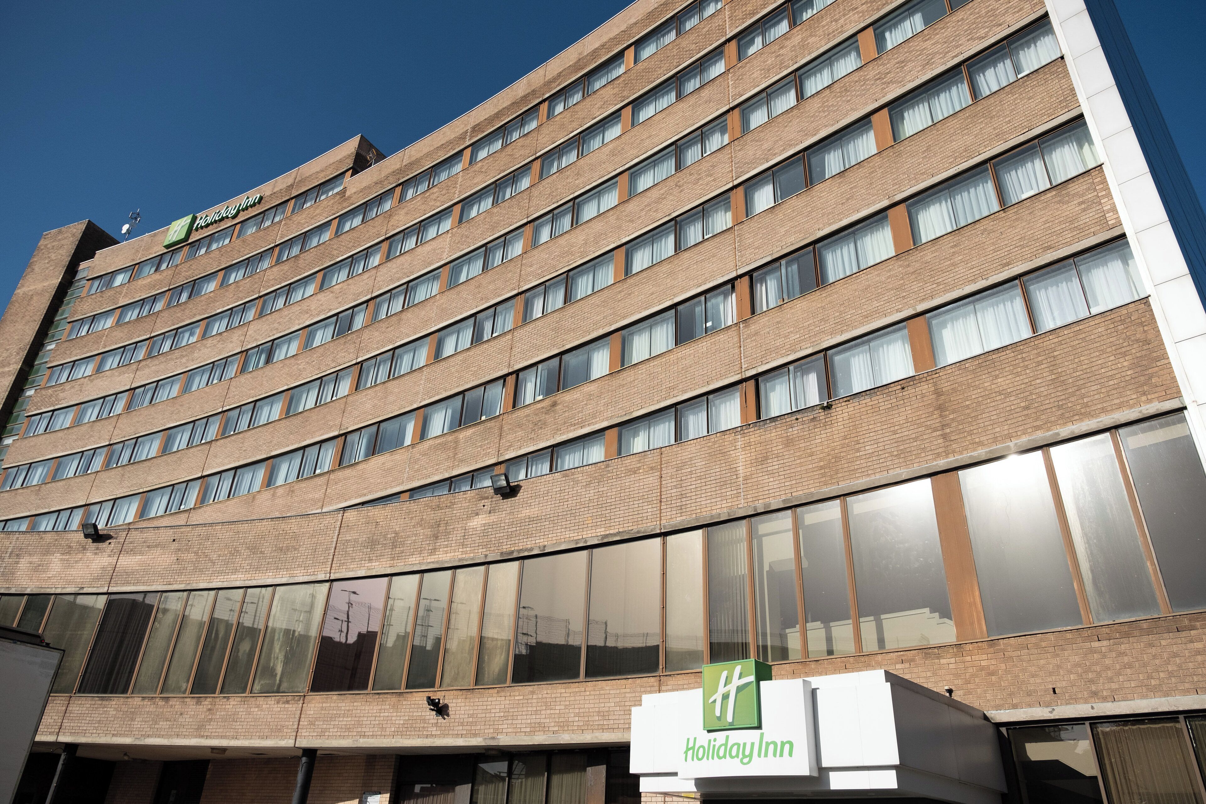 Ett flervåningshotell av märket Holiday Inn med en modern fasad av tegel och stora fönster.