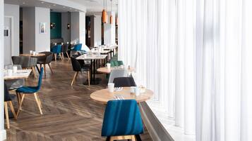 Un área de comedor moderna con mesas redondas, sillas e iluminación colgante.