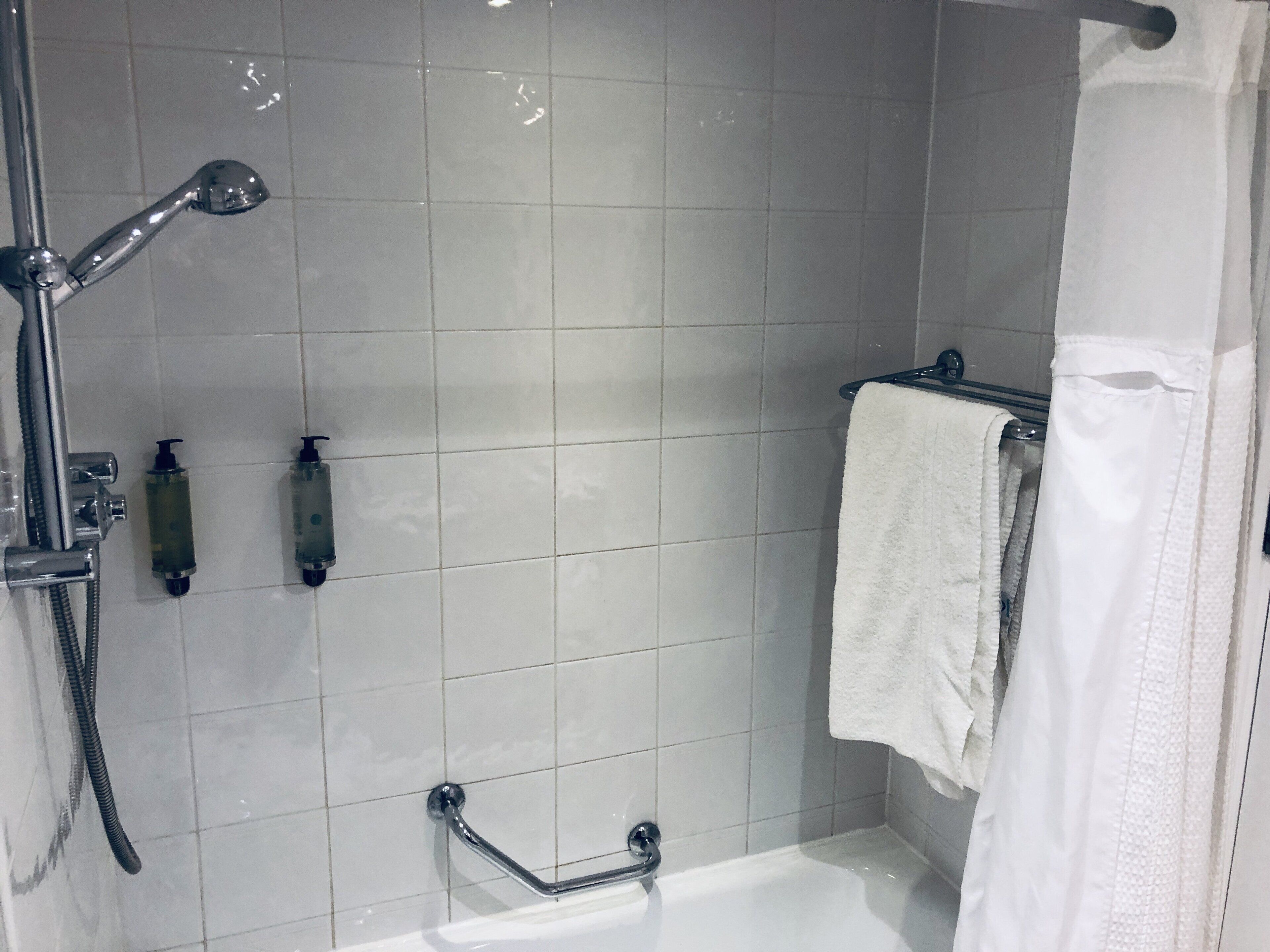 A bathroom with a shower, a bathtub, and a towel rack.